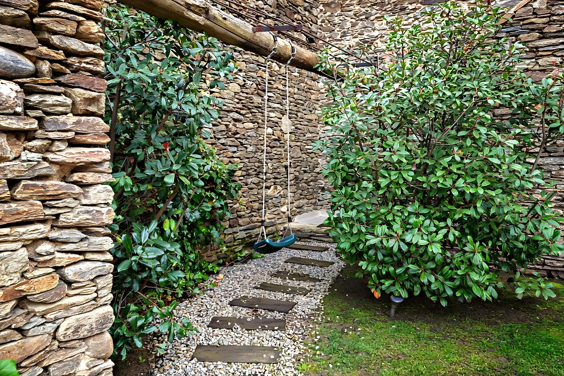 Pati de pedra seca amb vegetació i gronxador artesà